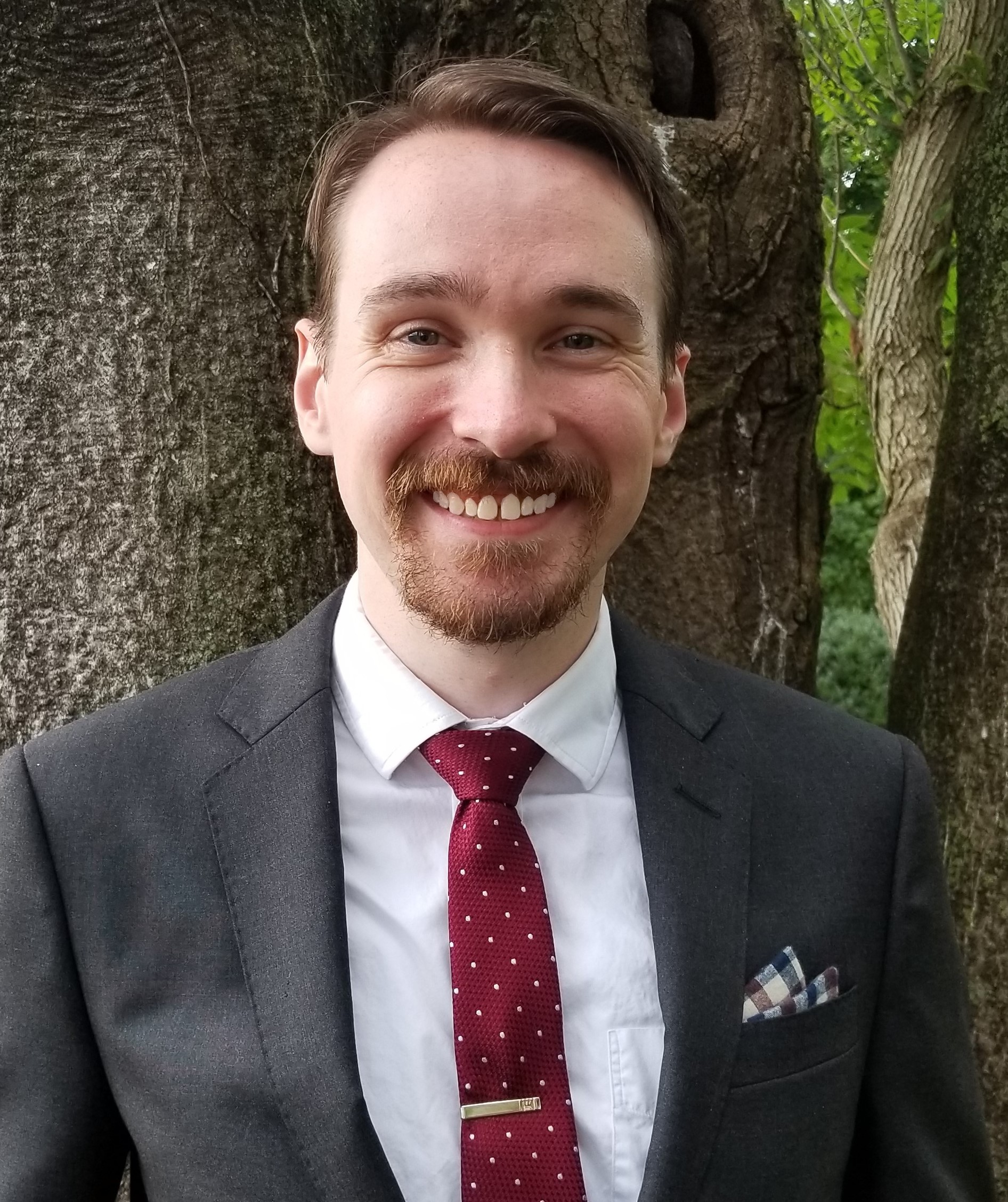 Headshot of TBS TL1 Scholar Kevin Cook, standing outside, smiling at the camera