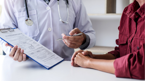 Image of a doctor holding a clipboard, reading to a female trial participant