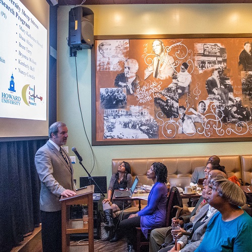 A medical doctor is giving a research presentation to an audience in a coffee shop